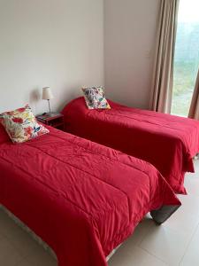 2 rote Betten in einem Zimmer mit Fenster in der Unterkunft La casita de La Rioja in La Rioja