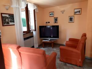 a living room with orange chairs and a flat screen tv at Hotel Brufa in Monteleone di Spoleto