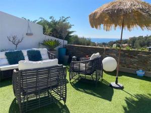 a patio with two chairs and an umbrella at VUEMER Bandol - GRANDE TERRASSE de 45m2 VUE MER PISCINE PARKING in Bandol