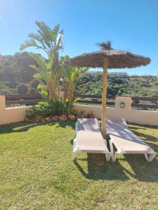 two lounge chairs and an umbrella on the grass at Coto Real Resort in Manilva