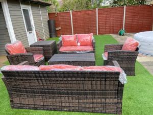 a patio with wicker chairs and a couch with red pillows at ANGIE HOME in Luton