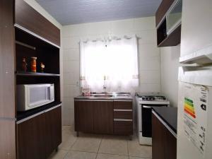 a small kitchen with a sink and a microwave at Casa próxima às Cataratas e Argentina/WIFI/garagem in Foz do Iguaçu