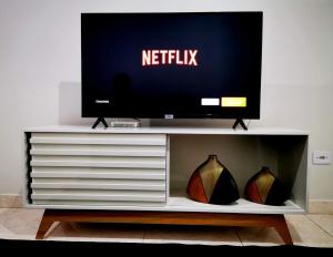 a television on top of a white entertainment center at Casa próxima às Cataratas e Argentina/WIFI/garagem in Foz do Iguaçu