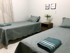 a bedroom with two beds and a night stand with a pillow at Casa próxima às Cataratas e Argentina/WIFI/garagem in Foz do Iguaçu