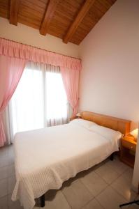 1 dormitorio con cama blanca y cortinas rosas en Apartamentos Siglo XXI - Ancla, en Sant Feliu de Guíxols