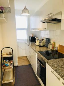 uma cozinha com armários brancos e um balcão preto em Super location 2, 1min metro 10 min from Camden em Londres