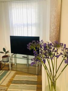 um vaso com flores roxas numa sala com televisão em Super location 2, 1min metro 10 min from Camden em Londres