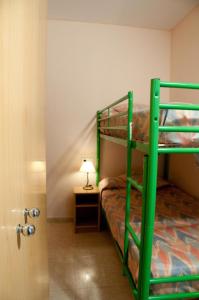 サン・フェリウ・デ・ギホルスにあるApartamentos Siglo XXI - Sant Joanのランプ付きのお部屋の緑色の二段ベッド1台分です。