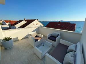 een patio met een bank en stoelen op een balkon bij Apartment Jakovcevic 3 in Zadar
