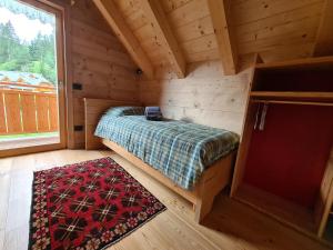 1 dormitorio en una cabaña de madera con cama y alfombra en Chalet Camporosso, en Camporosso in Valcanale