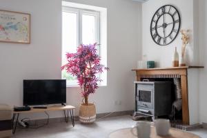een woonkamer met een tv en een open haard bij CABANA & LES PORTES DE LA FORÊT D' ORLÉANS in Nevoy