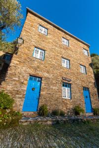 ein großes Backsteingebäude mit blauen Türen darauf in der Unterkunft Casa da Padaria in Piódão