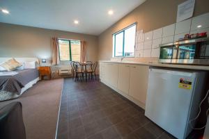 a room with a bed and a kitchen with a counter at Coronation Park Motels in Ashburton