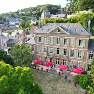 a large house with pink umbrellas in front of it at Demeure en Seine - Gîtes et chambres d'hôte en bord de Seine in Caudebec-en-Caux