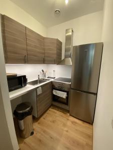 uma cozinha com um frigorífico em aço inoxidável e pisos em madeira em Villa des Thermes - T2 em Royat