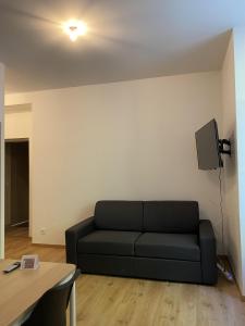 salon z czarną kanapą i telewizorem w obiekcie Villa des Thermes - T2 w mieście Royat