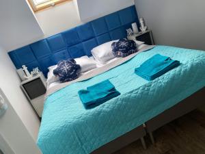 uma grande cama azul com duas almofadas azuis em "Blue Sun" Apartament 11B HorizonPark Dziwnòwek em Dziwnówek