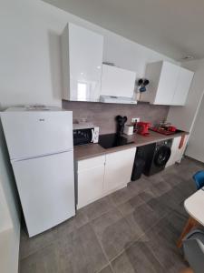 uma cozinha com armários brancos e um frigorífico branco em Superbe logement T3 en duplex. em Saint-Gaudens