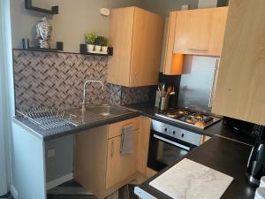 cocina con armarios de madera, fregadero y fogones en Pendle House Apartment 1, en Colwyn Bay 6 fotos más