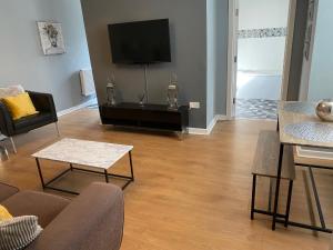 a living room with a couch and a tv at Pendle House Apartment 1 in Colwyn Bay