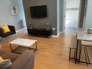 Una sala de estar con un sofá y un televisor. en Pendle House Apartment 1, en Colwyn Bay