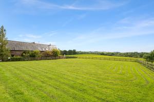a large green field with a fence and a house at House Martin in Ipplepen