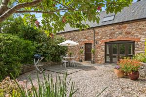a patio with a table and an umbrella in front of a building at House Martin in Ipplepen
