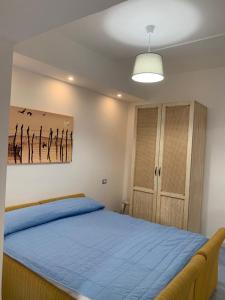 a bedroom with a blue bed with a painting on the wall at NERONE HOUSE in Diamante