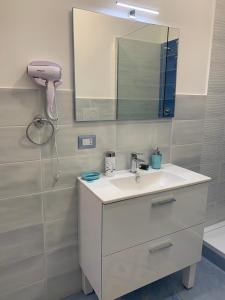 ein Badezimmer mit einem weißen Waschbecken und einem Spiegel in der Unterkunft NERONE HOUSE in Diamante