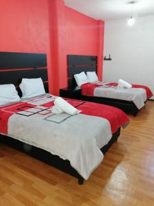 two beds in a room with red walls at Hotel Boutique Otomi cerca de Tolantongo in Cardonal