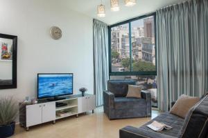 a living room with a couch and a tv and a window at H7 TLV in Tel Aviv