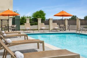 a swimming pool with chairs and umbrellas at Hyatt House Bryan/College Station in College Station