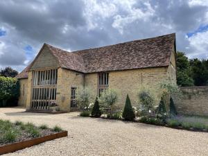a large stone building with a large roof at 17th Century Barn near Le Manoir aux Quat’Saisons in Great Milton