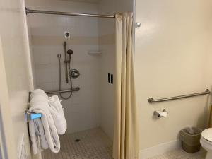a bathroom with a shower with towels and a toilet at Bide-A-Wee Inn and Cottages in Pacific Grove
