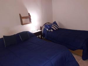 two beds in a room with blue sheets at Aires de Uspallata in Uspallata