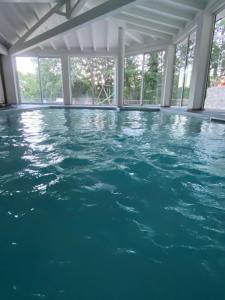 a swimming pool with blue water in a room with windows at Agriturismo il Vignale in Longi