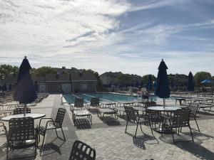 an outdoor patio with tables and chairs and a pool at Peaceful Pintail in Ocean Pines