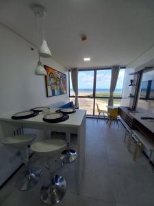 a kitchen and living room with a table and chairs at FLAT BEIRA MAR BARRA DE JANGADA RECIFE ANDAR ALTO in Recife