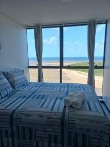 - une chambre avec un lit et une vue sur la plage dans l'établissement FLAT BEIRA MAR BARRA DE JANGADA RECIFE ANDAR ALTO, à Récife