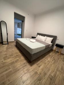 a bedroom with a bed and a wooden floor at AG.Stone.Home in Isthmia