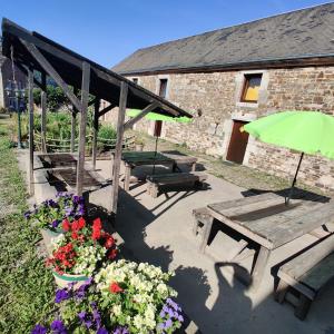 eine Gruppe von Picknicktischen und Blumen vor einem Gebäude in der Unterkunft La Ferme de Werpin in Hotton