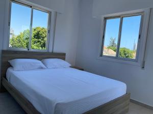 um quarto com uma cama branca e 2 janelas em 1-bedroom apartment with view em Limassol