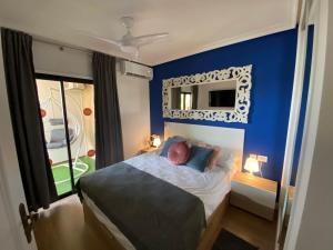 1 dormitorio con paredes azules y 1 cama con espejo en Villa Moleiro - Golf del Sur, en San Miguel de Abona