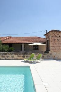 a swimming pool with two chairs and a house at O Pombal in Alcanena