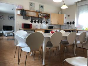 a kitchen with a table and white chairs at la Discrète in Berck-sur-Mer