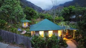 a house in the mountains with a green roof at Iao Valley Inn in Wailuku