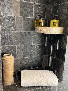 baño con pared de azulejos negros y toalla en Nobile Dimora di Puglia, en Ostuni
