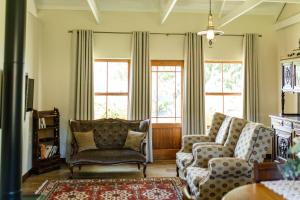 a living room with two chairs and two windows at Baris Guesthouse in Clarens