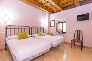2 camas en una habitación con TV en la pared en Hotel Rural Fuente del Val en Prádanos de Ojeda