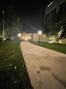 a sidewalk in a park at night with street lights at فيلا اورنيلا in Al Hada